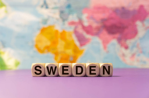 Слово "Швеція", написане з дерев'яними знаками перед фіолетовим фоном і географічною картою. - Фото, зображення
