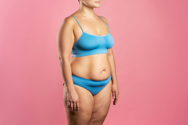 Fat woman in blue underwear on pink background, overweight female body, studio shot - Foto, immagini