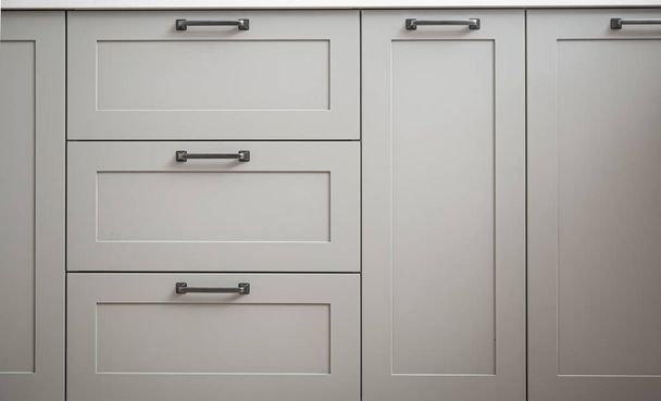 Bílé kuchyňské skříňky s kovovými táhly nebo knoflíky na dveřích zavřít. - Fotografie, Obrázek