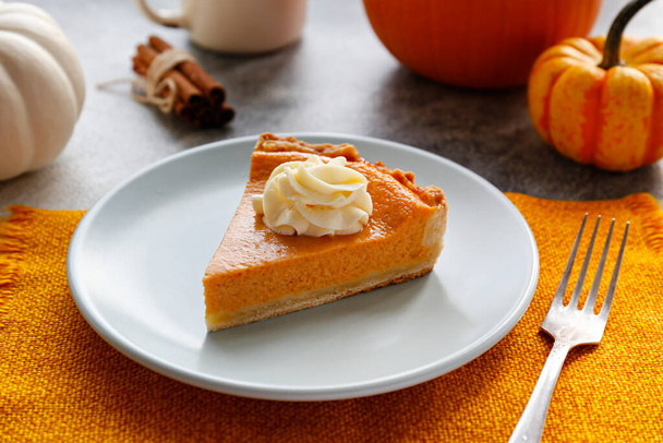 Traditional thanksgiving food on wooden table. Orange delicious homemade pumpkin pie with crust and decorative items. Thanksgiving table setting concept.Top view, close up, copy space, background. - 写真・画像