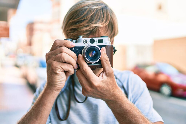 Молодой ирландский фотограф использует винтажную камеру на улице города. - Фото, изображение