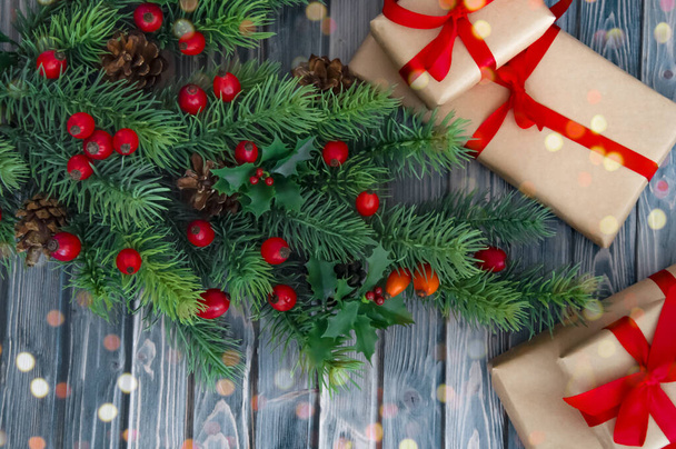 木製のテーブルの上にクリスマスツリー、コーン、赤い果実や贈り物の装飾枝。クリスマスの装飾. - 写真・画像
