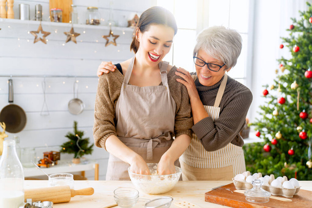 Mutlu Noeller ve mutlu tatiller. Aile hazırlığı bayram yemeği. Anne ve kızı zencefilli ekmek evi pişiriyor.. - Fotoğraf, Görsel