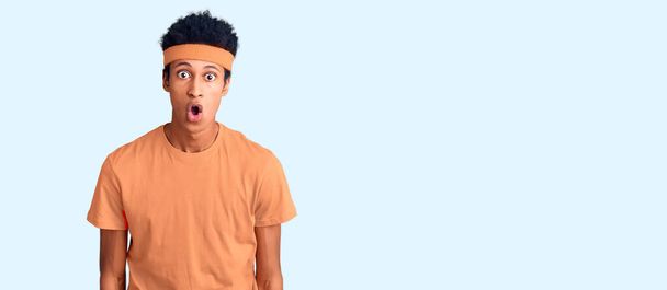 Joven afroamericano con ropa deportiva asustado y sorprendido con la boca abierta para sorpresa, cara de incredulidad  - Foto, Imagen