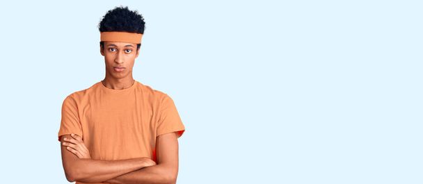 スポーツウェアを身に着けている若いアフリカ系アメリカ人男性は懐疑的で緊張しており、両腕を組んで顔を見つめて表現を否定している。否定的な人.  - 写真・画像