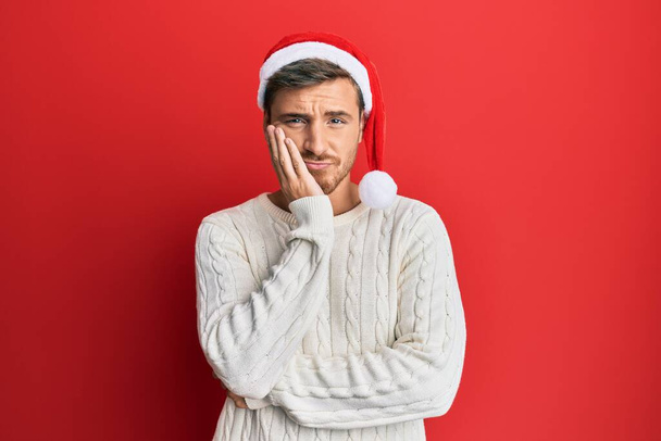 bel homme caucasien portant chapeau de Noël penser à la recherche fatigué et ennuyé avec des problèmes de dépression avec les bras croisés.  - Photo, image