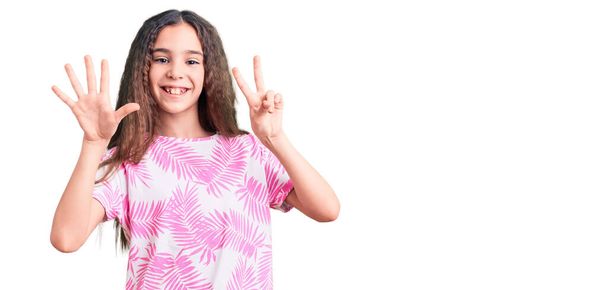 Мила дівчина з іспаномовним дитячим одягом, показуючи і вказуючи пальцями номер сім, посміхаючись впевнено і щасливо
.  - Фото, зображення