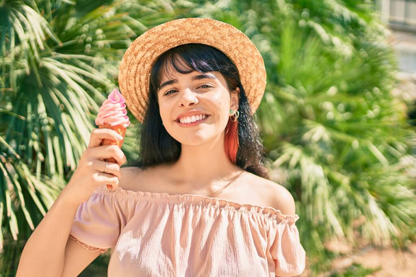 Mladý hispánský turista dívka na sobě letní styl jíst zmrzlinu v parku. - Fotografie, Obrázek