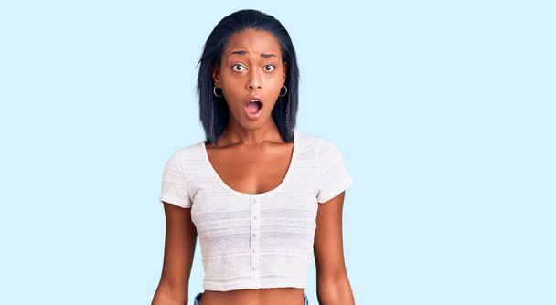 Mujer afroamericana joven con ropa casual asustada y sorprendida con la boca abierta para sorpresa, cara de incredulidad  - Foto, Imagen