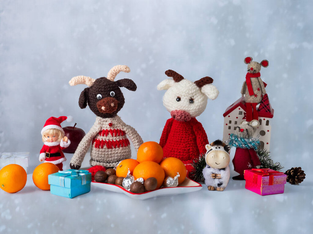 New year card with tangerines and knitted toys, the symbol of the chinese new year, white and brown bulls, and other festive toys and decor - Photo, Image