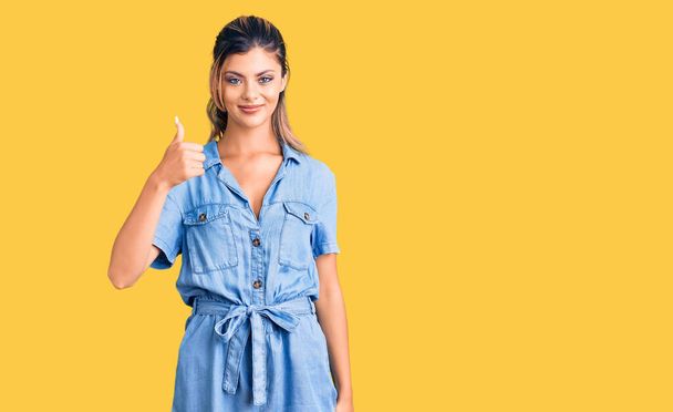 Young beautiful woman wearing casual clothes doing happy thumbs up gesture with hand. approving expression looking at the camera showing success.  - Fotoğraf, Görsel
