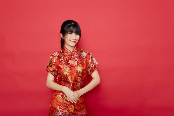 Linda mujer asiática joven usar cheongsam con la acción para el concepto de año nuevo chino sobre un fondo rojo - Foto, Imagen