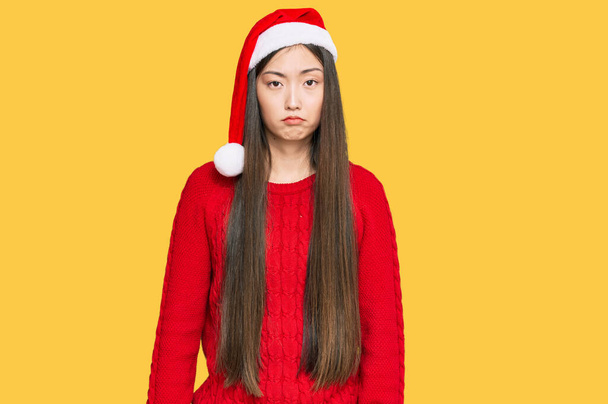 Młoda Chinka w świątecznym kapeluszu przygnębiona i martwiąca się o cierpienie, płacząca wściekła i przerażona. smutna ekspresja.  - Zdjęcie, obraz