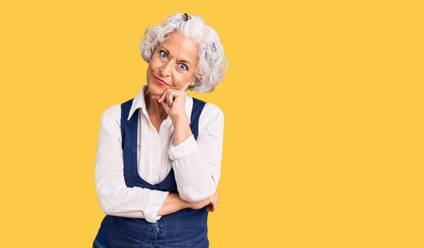 Starsza siwowłosa kobieta ubrana w luźne ubrania myśląca wyglądająca na zmęczoną i znudzoną problemami z depresją z skrzyżowanymi ramionami.  - Zdjęcie, obraz