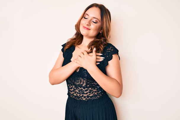 Young beautiful caucasian woman wearing elegant clothes smiling with hands on chest with closed eyes and grateful gesture on face. health concept.  - Photo, Image
