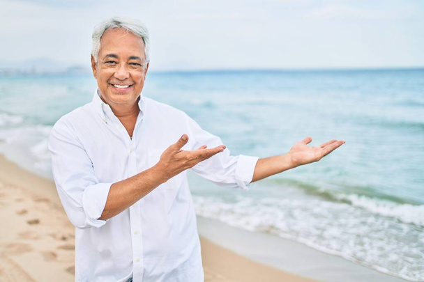 Handosme його латиноамериканський чоловік з сірим волоссям посміхається щасливим на пляжі, насолоджуючись відпусткою, вказуючи на місце для тексту
 - Фото, зображення