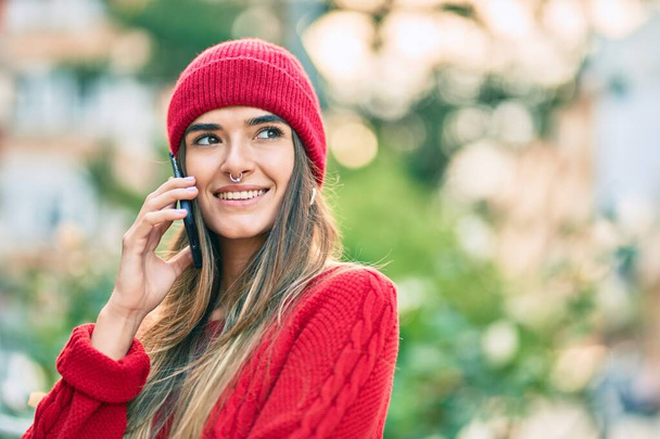 Young hispanic woman wearing winter style talking on the smartphone at the city. - Photo, Image