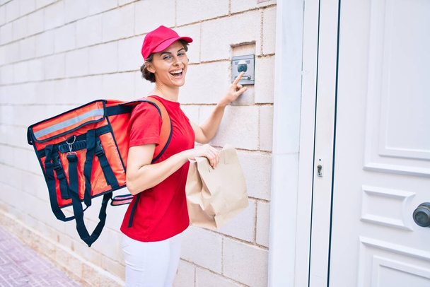 Entrega mulher trabalhador de negócios vestindo uniforme sorrindo feliz batendo na porta - Foto, Imagem