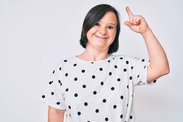 Brunette woman with down syndrome wearing casual clothes pointing finger up with successful idea. exited and happy. number one.  - Photo, Image