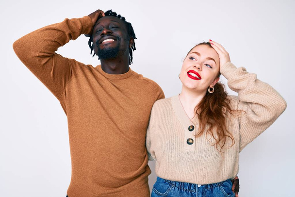 Διαφυλετικό ζευγάρι φορώντας casual ρούχα χαμογελώντας αυτοπεποίθηση αγγίζοντας τα μαλλιά με το χέρι προς τα πάνω χειρονομία, θέτοντας ελκυστική και μοντέρνα  - Φωτογραφία, εικόνα