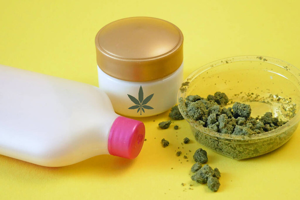 Crema cosmetica alle erbe in dose con pianta di marijuana su fondo giallo. Cosmetici a base di cannabis, primo piano - Foto, immagini
