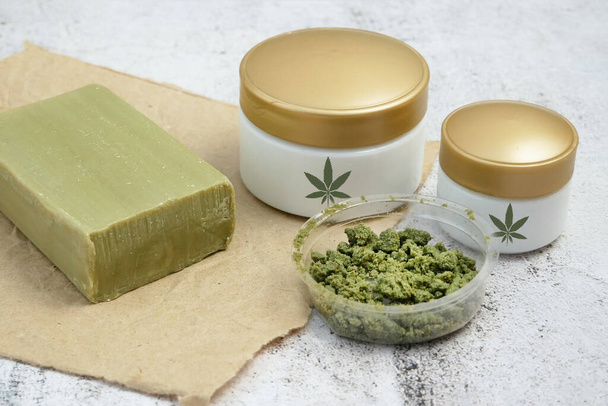 Kräutercreme Kosmetik in Dosis mit Marihuana-Pflanze auf gelbem Hintergrund. Cannabis-Kosmetik, Nahaufnahme - Foto, Bild