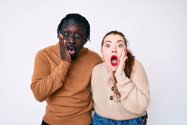 interraciaal paar dragen casual kleding bang en geschokt, verrassing en verbaasd uitdrukking met handen op het gezicht  - Foto, afbeelding