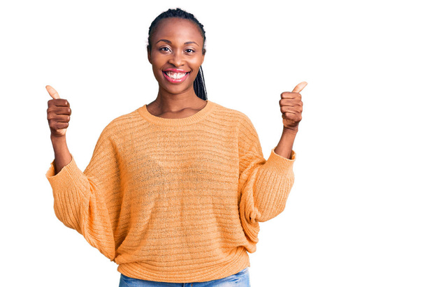 Mujer afroamericana joven con ropa casual signo de éxito haciendo gesto positivo con la mano, pulgares hacia arriba sonriendo y feliz. expresión alegre y gesto ganador.  - Foto, Imagen