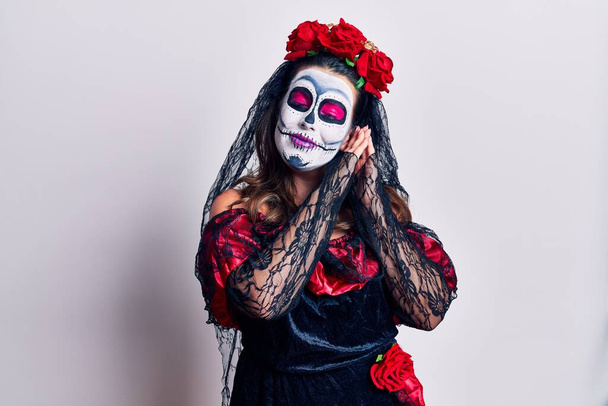 Young woman wearing day of the dead costume over white sleeping tired dreaming and posing with hands together while smiling with closed eyes.  - Photo, Image