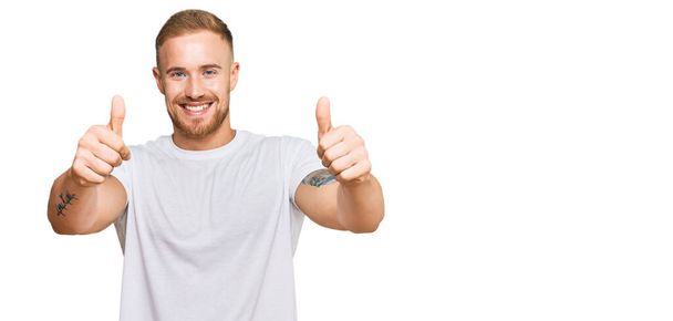 Junger irischer Mann in lässiger Kleidung, der zustimmend positive Gesten mit der Hand macht, Daumen hoch lächelnd und glücklich über den Erfolg. Siegergeste.  - Foto, Bild