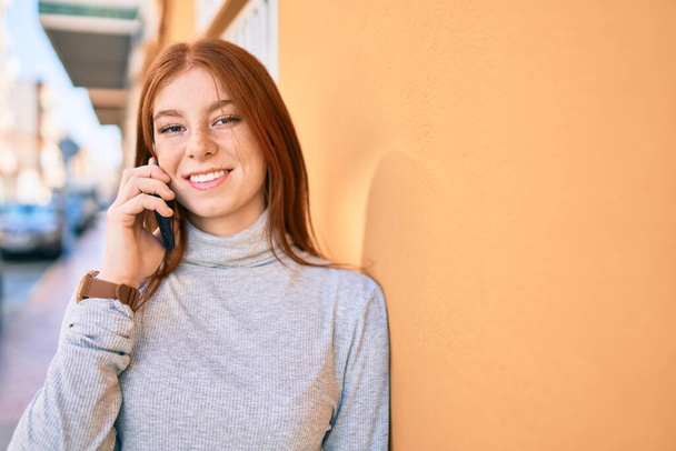 Fiatal ír tinédzser lány mosolyog boldog beszél az okostelefonon a városban. - Fotó, kép