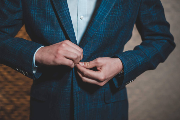 A shallow focus of an adult male buttoning up his blue jacket with a blurry background - Foto, Imagem