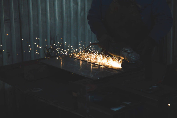 a worker  using a grinder machine on the glass and the flying sparkles - Fotoğraf, Görsel