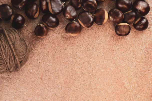 A top view of chestnuts with yarn on a corkboard - Fotó, kép