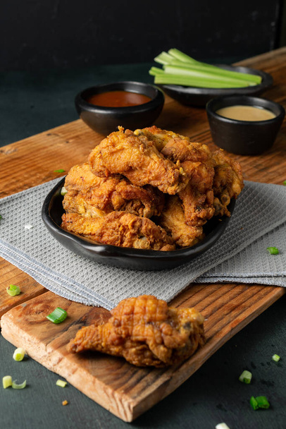 A vertical shot of delicious crispy fried chicken, ketchup, gravy and celery sticks on a wooden table - Photo, Image