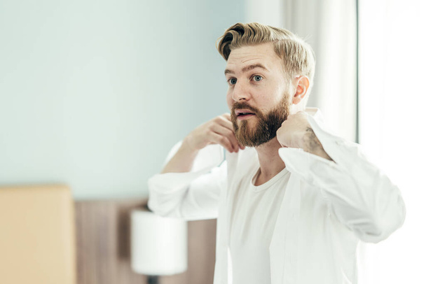 A shallow focus of a young male with a beard wearing a white shirt in a room - Foto, Bild