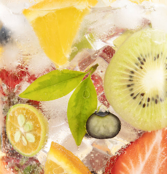 A closeup shot of a refreshing drink with sliced citrus fruits and ice cubes - Photo, Image