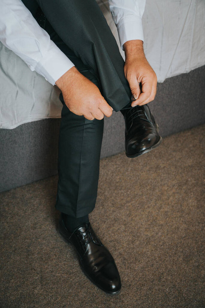 A vertical shot of the groom fixing his shoelaces - Photo, Image
