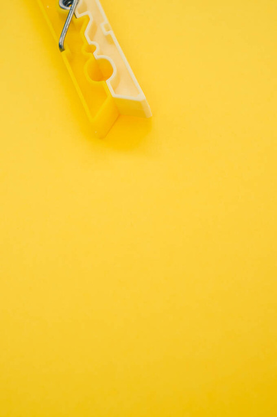 A vertical shot of plastic clothespin isolated on yellow background - 写真・画像