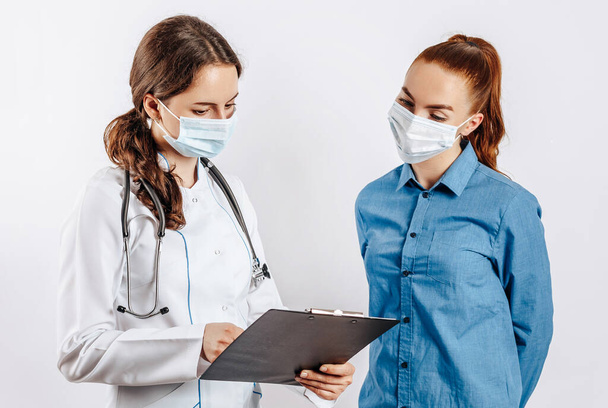 Woman patient at doctor in masks at reception to check health on white isolated background - Foto, Imagen