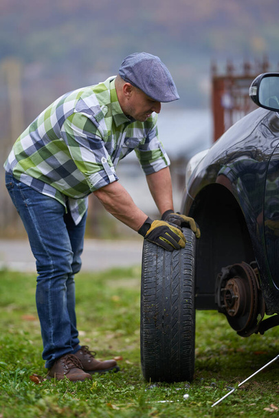 Man changing a flat tyre on his car by himself - Фото, зображення