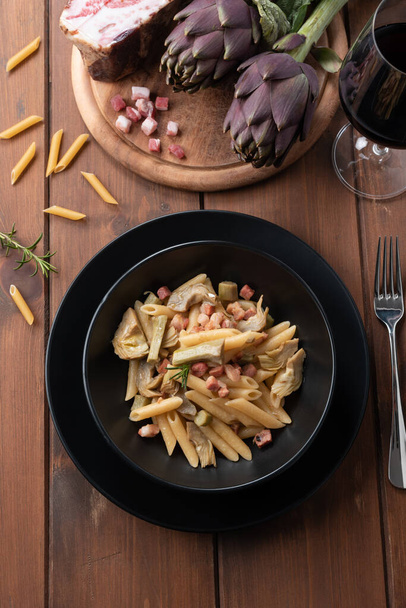Dish of delicious penne pasta with bacon and artichoke, Italian Cuisine - Photo, Image