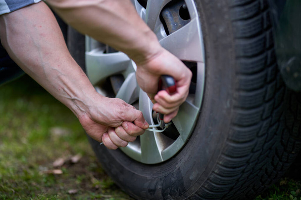 Man changing a flat tyre on his car by himself - Photo, Image