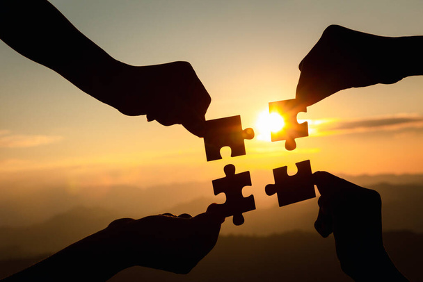 Силуэт руки, соединяющие головоломки против восхода солнца, бизнес-решений, совместной работы, партнерства, успеха, целей и стратегий. - Фото, изображение