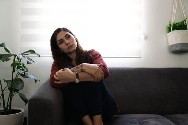 Jovem hispânica com problemas psicológicos sentada no sofá. Mulher deprimida e solitária em sua casa - Foto, Imagem