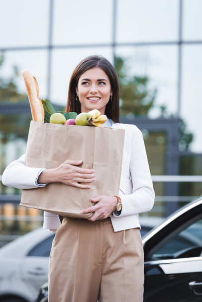 happy woman looking away while carrying shopping bag with food - Fotoğraf, Görsel