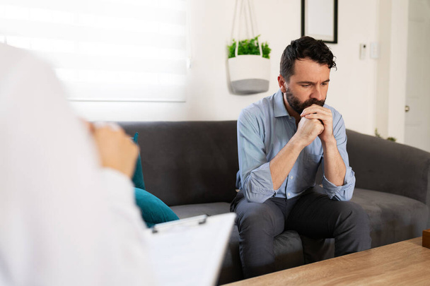 Hispanic adult man with depression and anxiety listening to the professional advice of his female psychiatrist  - Fotoğraf, Görsel