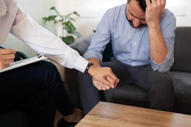 Primer plano de una psicóloga que ayuda y consuela a un paciente masculino deprimido durante una sesión de terapia profesional  - Foto, Imagen