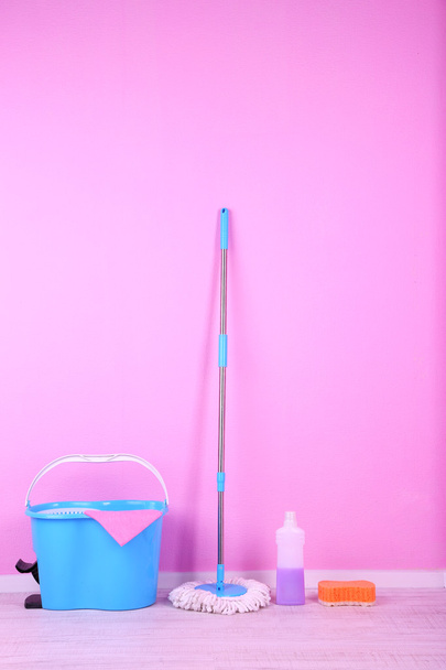 Floor mop and bucket for washing in room on pink wall background - Foto, Imagen