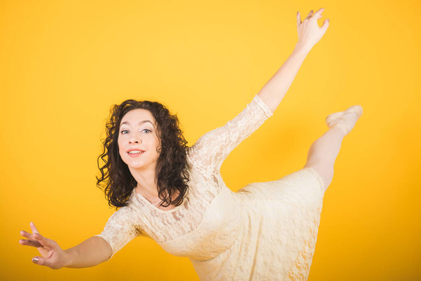 Graceful classic ballerina dancing on yellow studio background - Photo, image